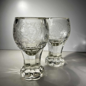 Pair of stemmed glasses in thick cut crystal with scrollwork and monogram decoration, Bohemia ca 1900