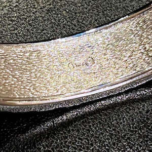 Christian DIOR, bracelet with silvered logo on bluish-grey background