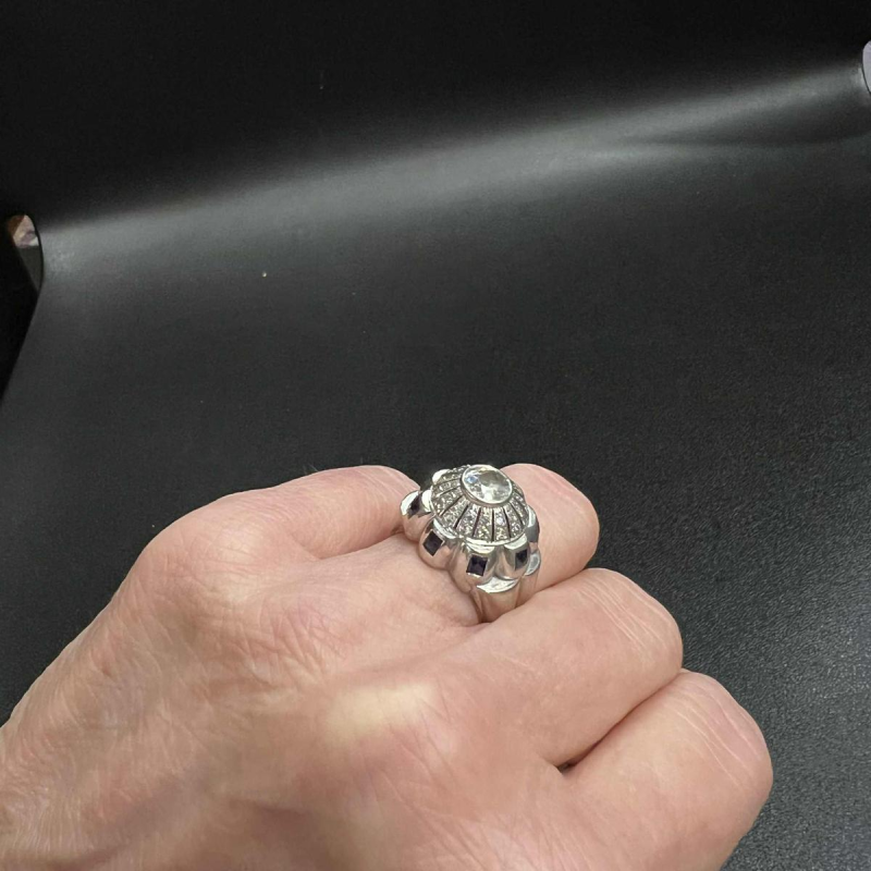 Bague en or blanc 18K sertie d’un diamant central entouré de petits diamants et de saphirs