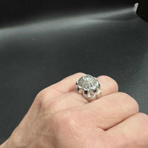 Bague en or blanc 18K sertie d’un diamant central entouré de petits diamants et de saphirs