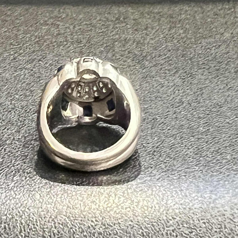 Bague en or blanc 18K sertie d’un diamant central entouré de petits diamants et de saphirs