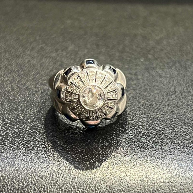 18K white gold ring set with a central diamond surrounded by smaller diamonds and sapphires