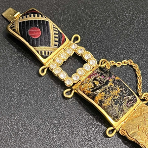 Christian LACROIX, beweegbare manchetarmband in goudkleurig metaal, met strass-steentjes en brokaatmotieven.