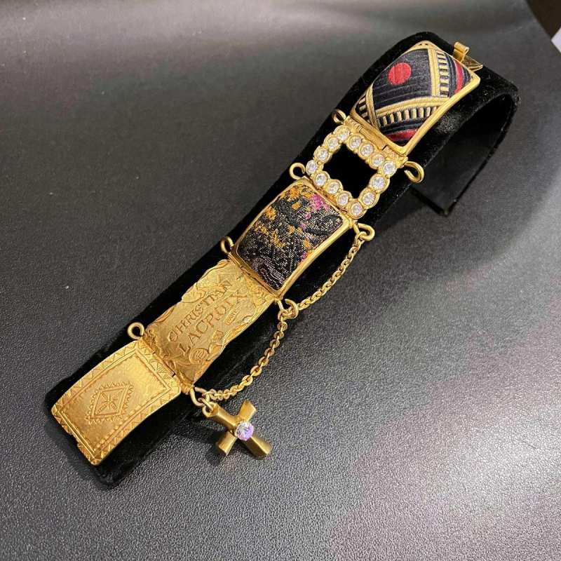 Christian LACROIX, beweegbare manchetarmband in goudkleurig metaal, met strass-steentjes en brokaatmotieven.