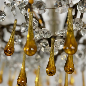 Achtarmige kroonluchter met hangers, in brons en kristal, met druppels van amberkleurig glas, circa 1900.