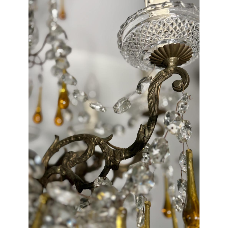 Achtarmige kroonluchter met hangers, in brons en kristal, met druppels van amberkleurig glas, circa 1900.