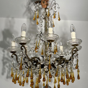 Achtarmige kroonluchter met hangers, in brons en kristal, met druppels van amberkleurig glas, circa 1900.
