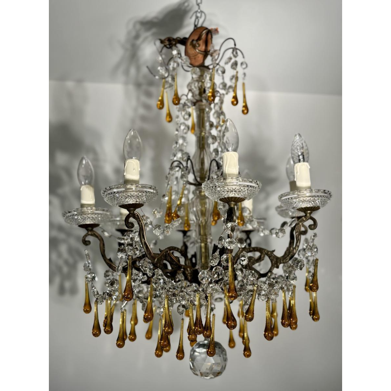Achtarmige kroonluchter met hangers, in brons en kristal, met druppels van amberkleurig glas, circa 1900.