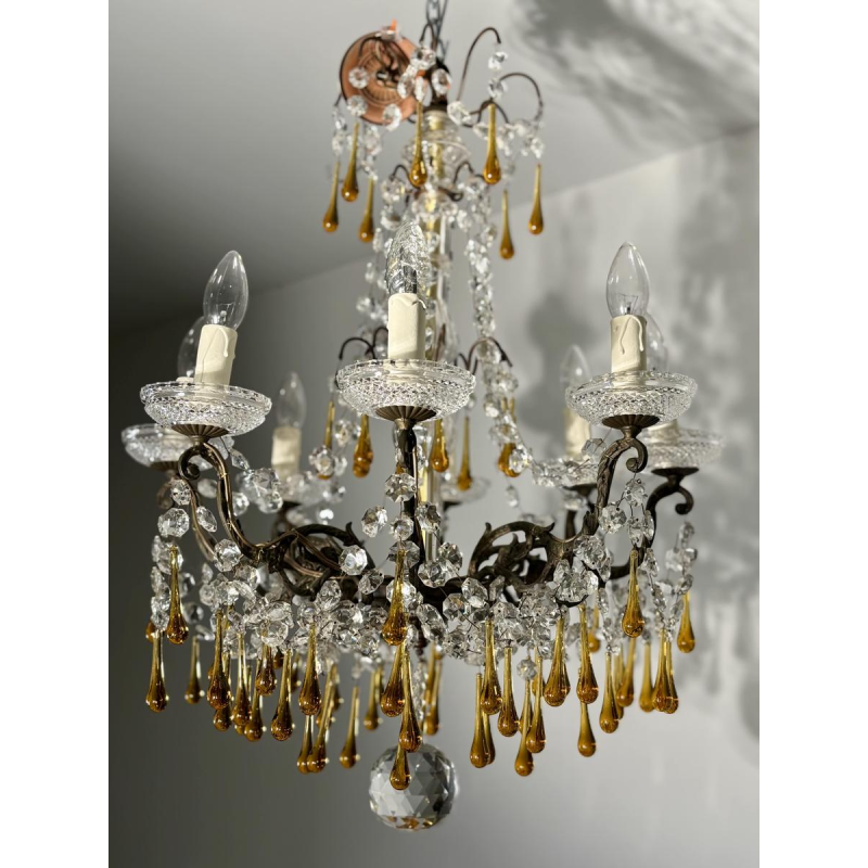 Achtarmige kroonluchter met hangers, in brons en kristal, met druppels van amberkleurig glas, circa 1900.