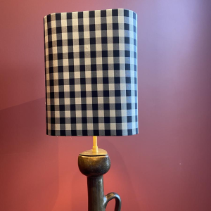 Bronzen tafellamp met een zwart-wit geblokte zijden lampenkap.