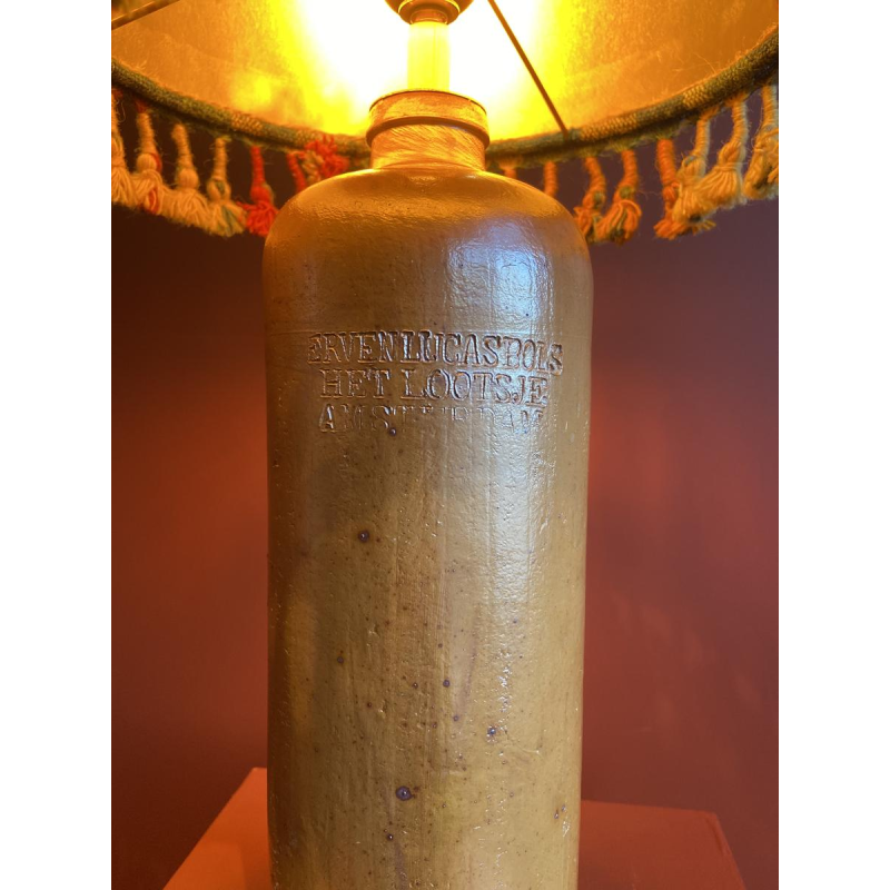 Lamp in de vorm van een "stenen fles" met een blauwe en veelkleurige lampenkap, handgeweven in India.