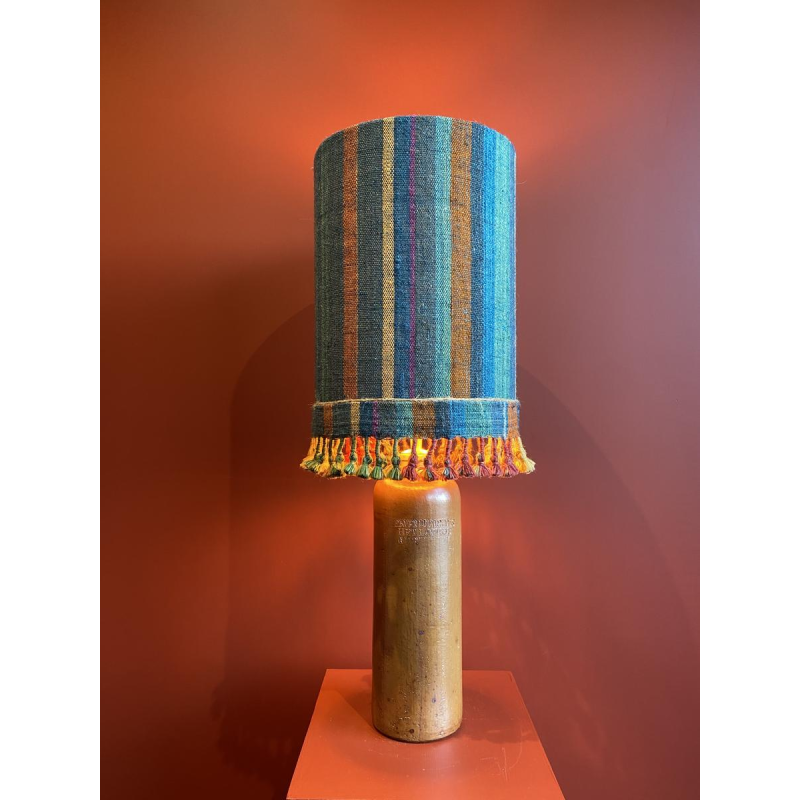 Lamp in de vorm van een "stenen fles" met een blauwe en veelkleurige lampenkap, handgeweven in India.