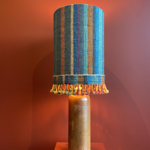 Lamp in de vorm van een "stenen fles" met een blauwe en veelkleurige lampenkap, handgeweven in India.