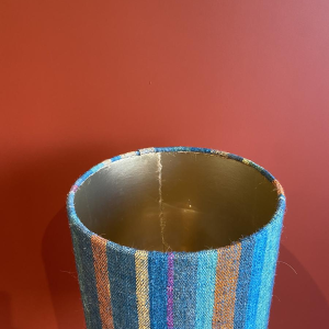 Lamp in de vorm van een "stenen fles" met een blauwe en veelkleurige lampenkap, handgeweven in India.