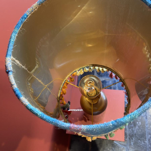 Lamp in de vorm van een "stenen fles" met een blauwe en veelkleurige lampenkap, handgeweven in India.