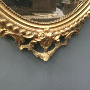 Louis XV oval mirror with pediment, wood and gilt stucco, beveled glass, Napoleon III