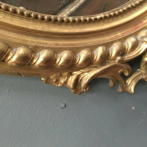 Miroir Louis VX ovale à fronton, bois et stuc doré, glace biseautée, Napoléon III