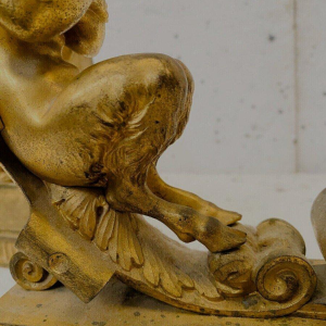 Een paar verguld bronzen haardijzers versierd met gevleugelde faunen, 19e eeuw.